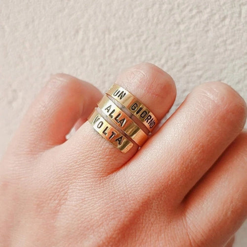 Mano che indossa anello a tre giri con scritta Un giorno alla volta